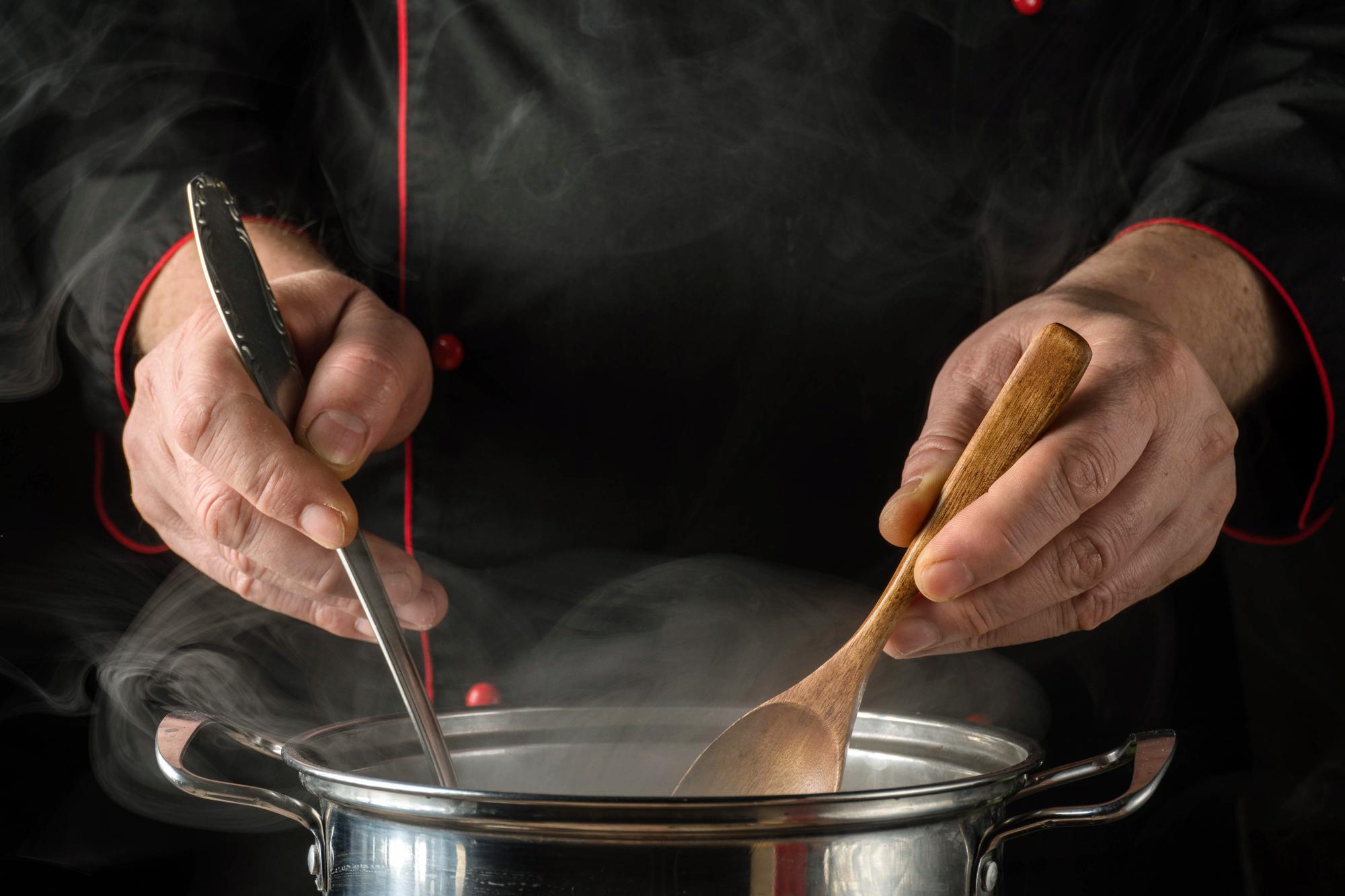 Chef at stove stirring a sauce